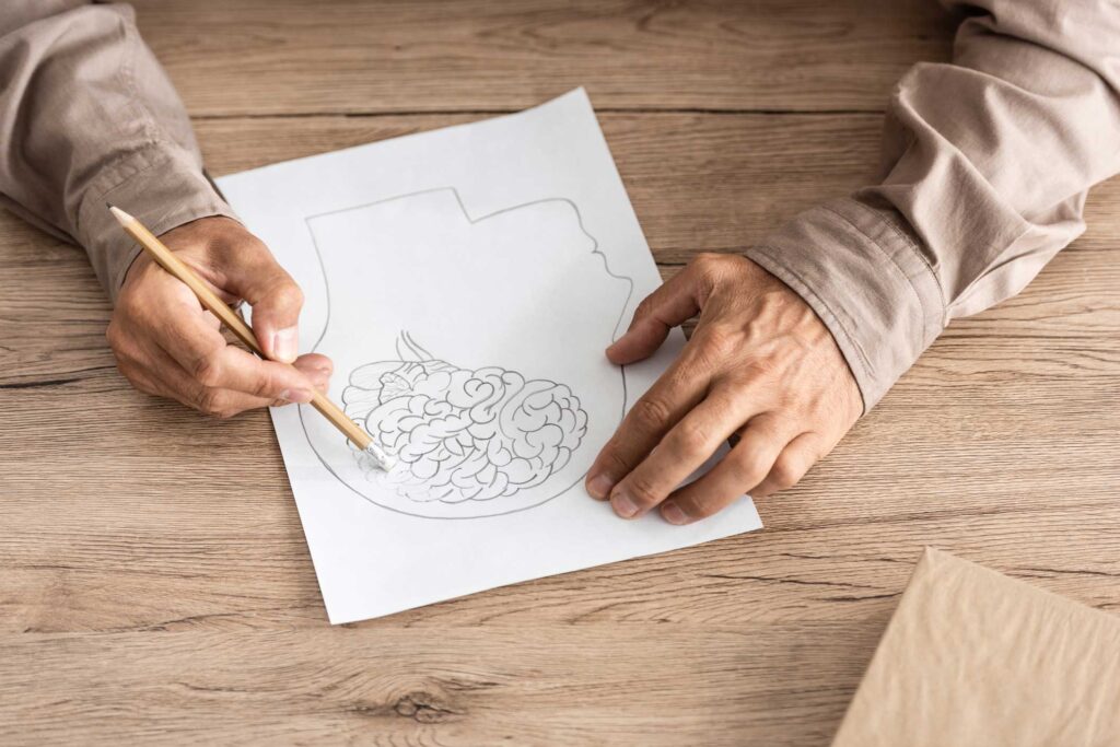 cropped view of elderly man erasing a drawing of a brain to symbolize struggle with Alzheimer's or dementia